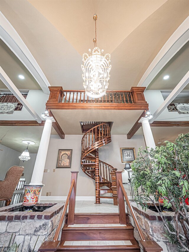 staircase featuring a high ceiling, a chandelier, and decorative columns