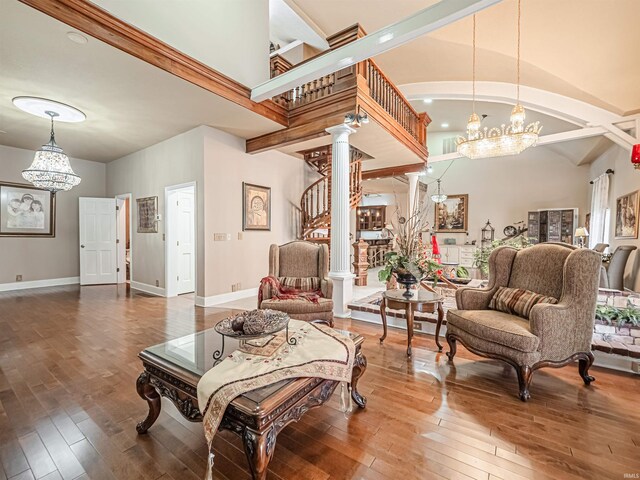 living area with high vaulted ceiling, dark hardwood / wood-style flooring, ornate columns, and an inviting chandelier