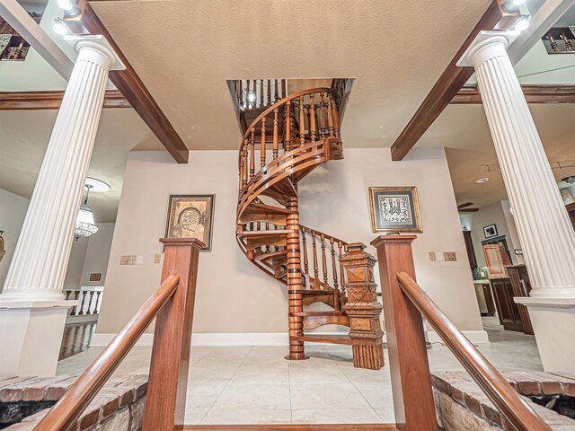 staircase with light tile flooring, ornate columns, and a textured ceiling