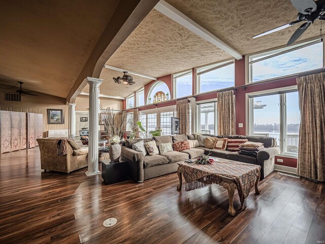 living room with high vaulted ceiling, dark hardwood / wood-style floors, ceiling fan, and decorative columns