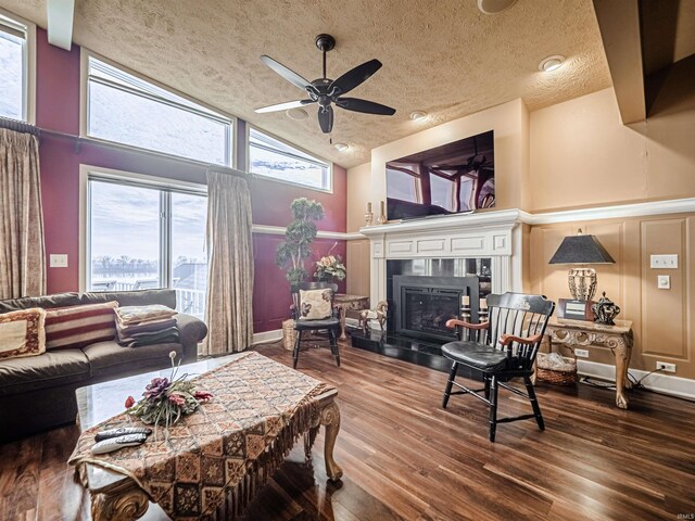 living room featuring ceiling fan, dark hardwood / wood-style flooring, plenty of natural light, and a textured ceiling