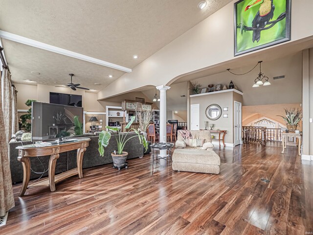 living room featuring a textured ceiling, high vaulted ceiling, ceiling fan with notable chandelier, dark hardwood / wood-style flooring, and decorative columns