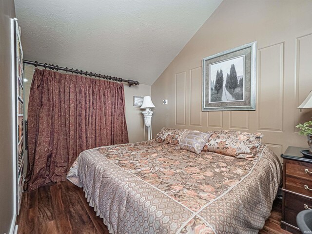 bedroom featuring a textured ceiling, dark hardwood / wood-style flooring, and vaulted ceiling