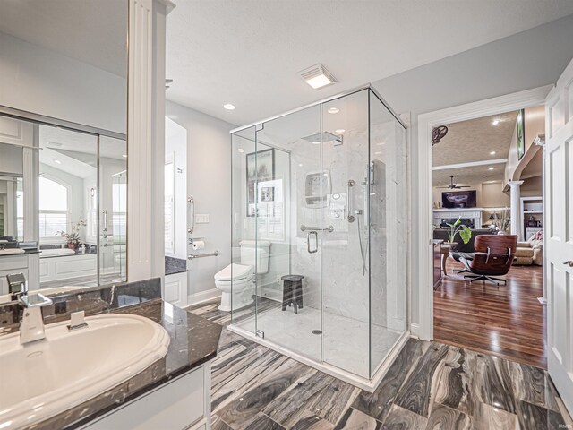 bathroom featuring walk in shower, decorative columns, toilet, wood-type flooring, and vanity