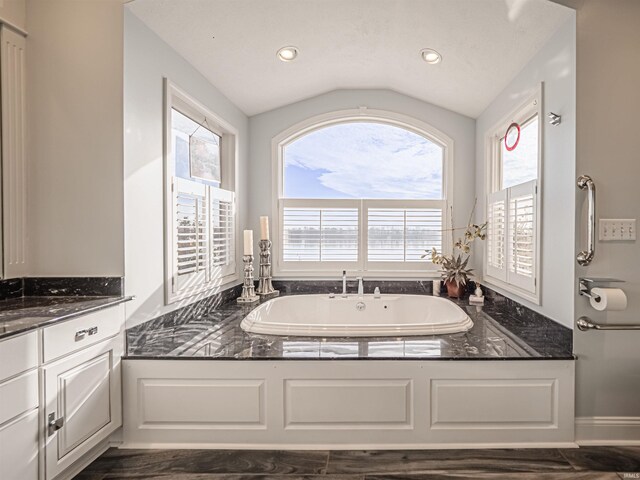 bathroom featuring lofted ceiling, vanity, and a bathing tub