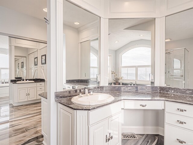 bathroom with walk in shower, vaulted ceiling, and vanity