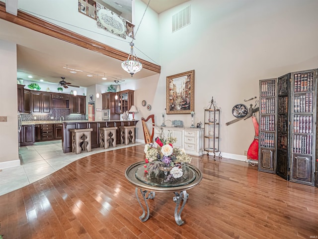 interior space with ceiling fan, light tile flooring, and a high ceiling