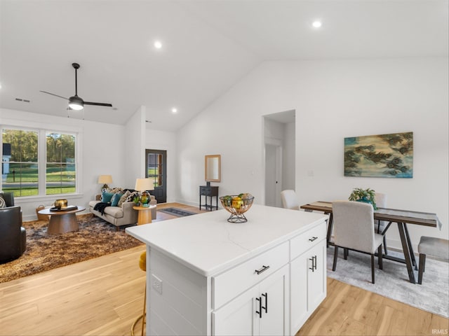 kitchen featuring white cabinetry, light hardwood / wood-style floors, ceiling fan, vaulted ceiling, and a center island