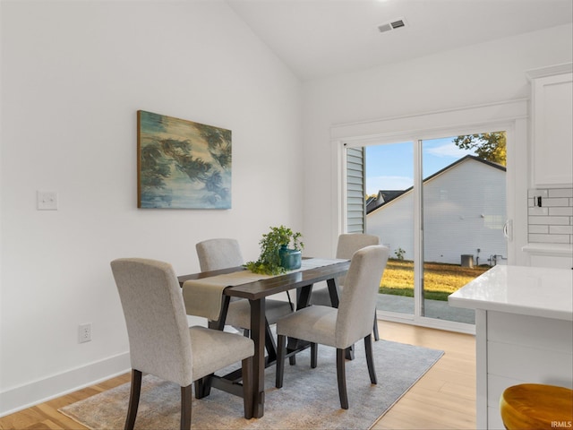 dining space with light wood-type flooring and vaulted ceiling