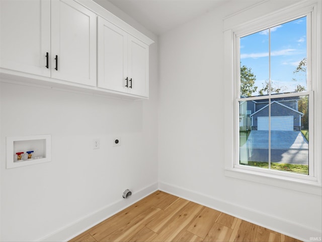 laundry area with cabinets, electric dryer hookup, a healthy amount of sunlight, hookup for a washing machine, and light hardwood / wood-style flooring