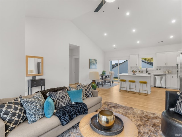 living room featuring light hardwood / wood-style floors, sink, lofted ceiling, and ceiling fan