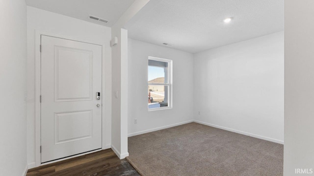 carpeted entrance foyer featuring a textured ceiling