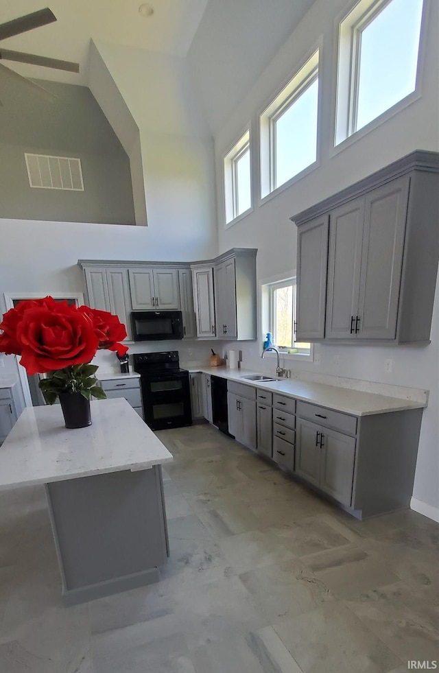 kitchen featuring black appliances, sink, ceiling fan, gray cabinets, and a towering ceiling