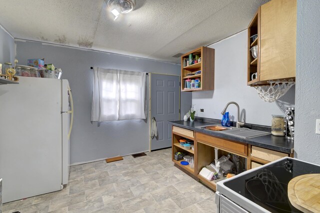 kitchen featuring white refrigerator, sink, a textured ceiling, stove, and light tile patterned flooring