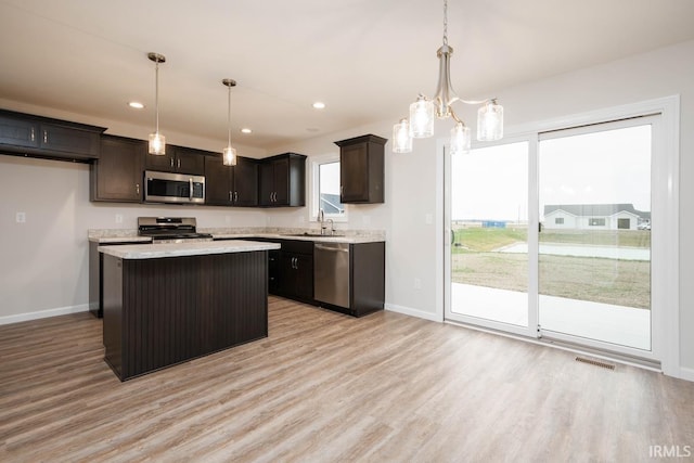 kitchen with hanging light fixtures, appliances with stainless steel finishes, a center island, and sink