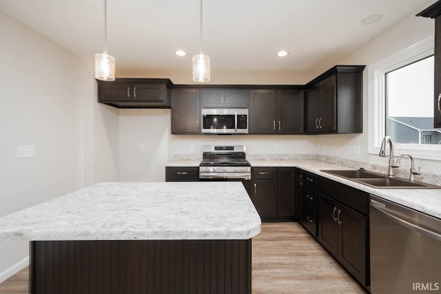 kitchen featuring stainless steel appliances, decorative light fixtures, a center island, and sink