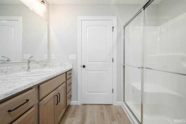 bathroom featuring a shower with door, vanity, and hardwood / wood-style flooring