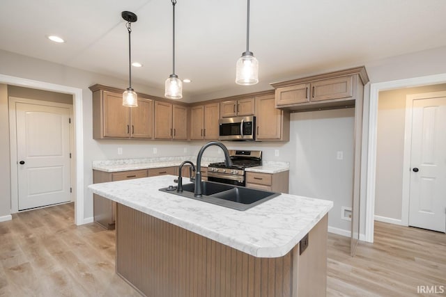 kitchen with stainless steel appliances, pendant lighting, sink, and a center island with sink