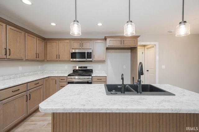 kitchen featuring sink, decorative light fixtures, an island with sink, and appliances with stainless steel finishes