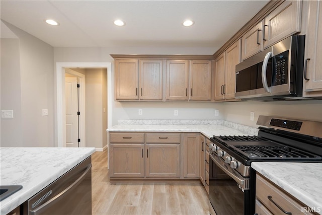 kitchen featuring light stone countertops, appliances with stainless steel finishes, and light hardwood / wood-style flooring