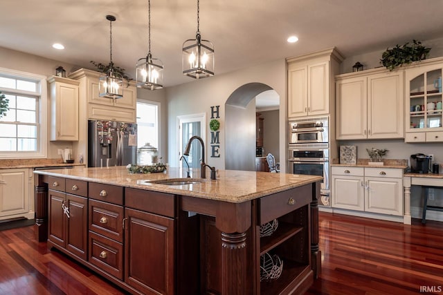 kitchen featuring dark brown cabinetry, sink, dark wood-type flooring, hanging light fixtures, and stainless steel appliances