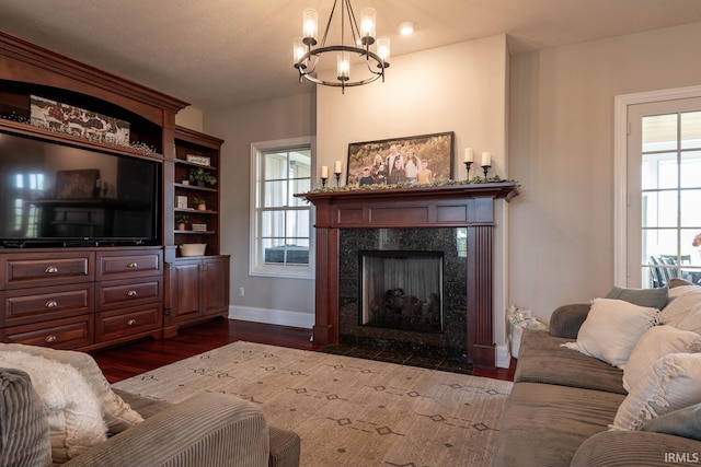 living room featuring wood-type flooring, a notable chandelier, and a premium fireplace