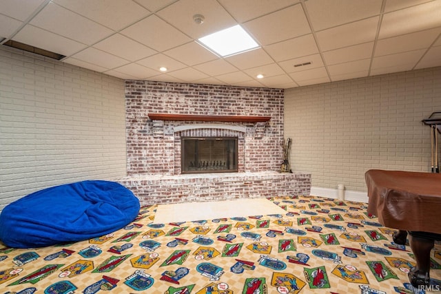 bedroom with brick wall, a paneled ceiling, and a brick fireplace