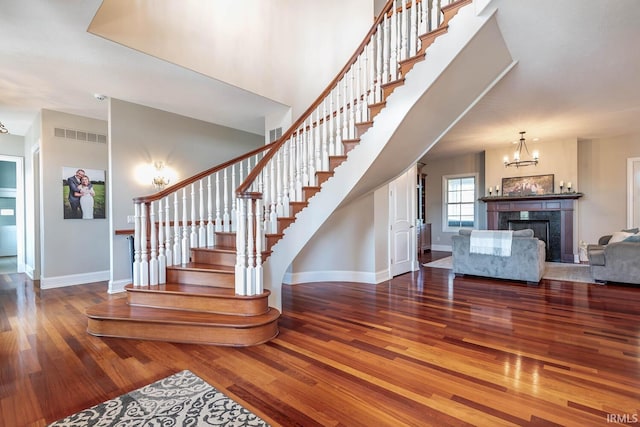 stairway featuring wood-type flooring and an inviting chandelier