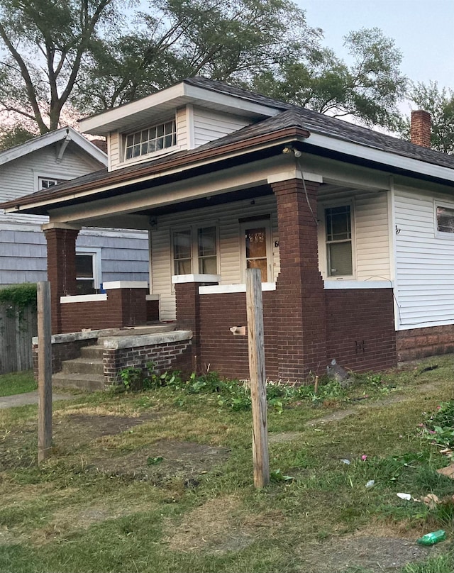 bungalow with a porch and a front lawn