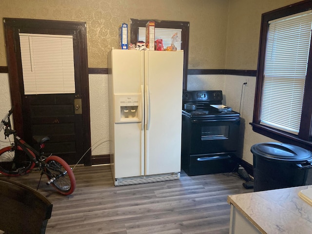 kitchen featuring black range with electric cooktop, white refrigerator with ice dispenser, and hardwood / wood-style floors