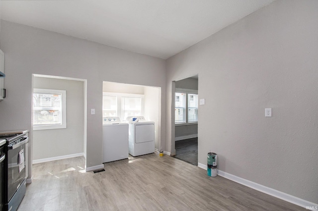 washroom with washer and clothes dryer, light hardwood / wood-style flooring, and a healthy amount of sunlight