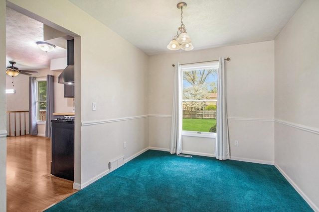 carpeted empty room featuring ceiling fan with notable chandelier