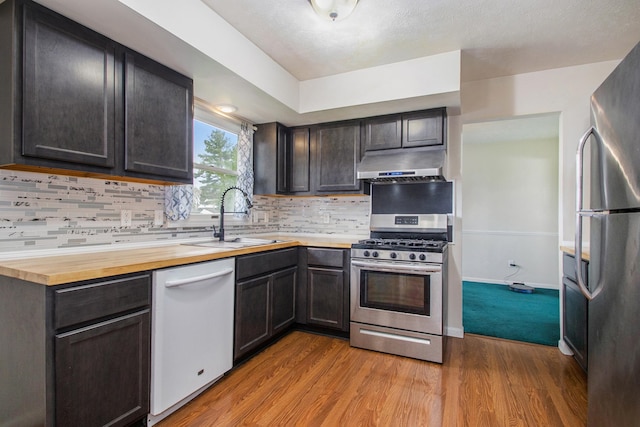 kitchen featuring appliances with stainless steel finishes, tasteful backsplash, light hardwood / wood-style floors, and butcher block counters