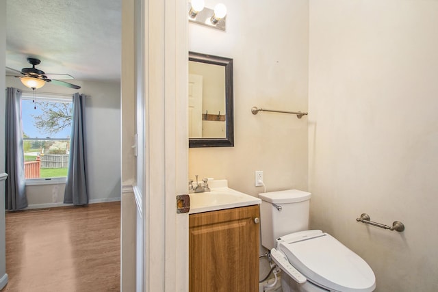 bathroom with vanity, hardwood / wood-style flooring, toilet, ceiling fan, and a textured ceiling