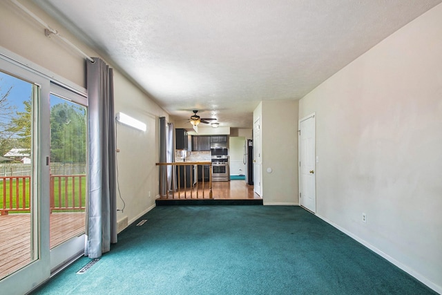 unfurnished room featuring ceiling fan, dark carpet, and a textured ceiling