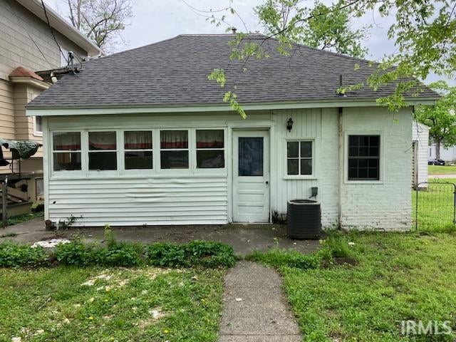 rear view of property featuring central AC and a lawn