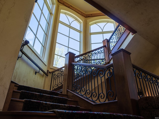 stairs featuring a towering ceiling and decorative columns