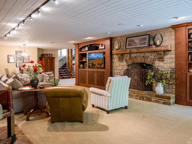 carpeted living room featuring rail lighting and a stone fireplace