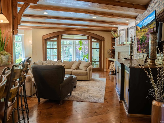 living room featuring wood-type flooring, beam ceiling, and plenty of natural light