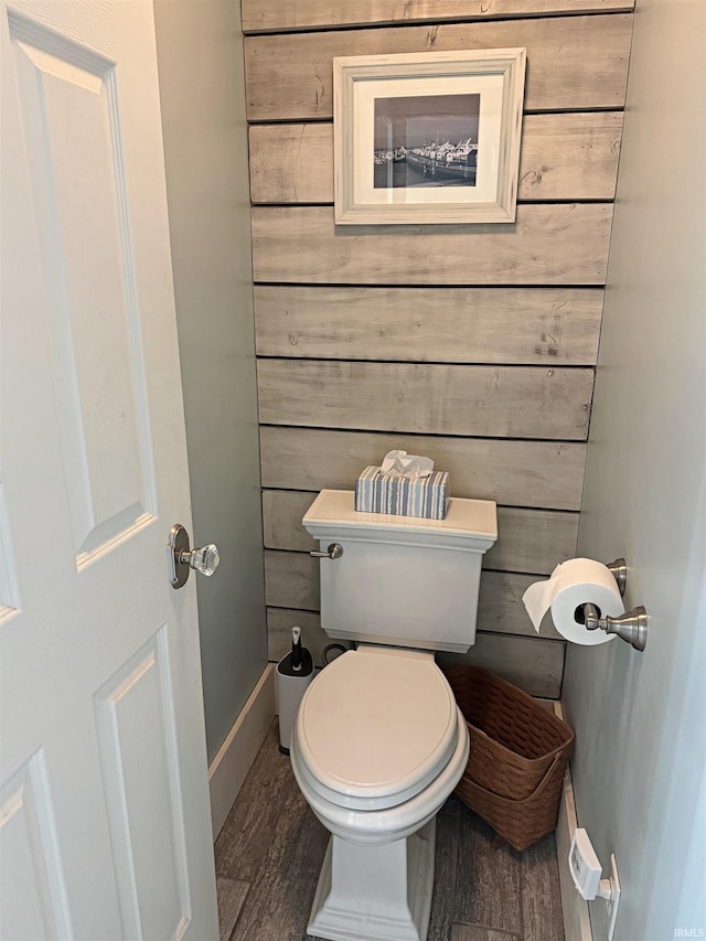 bathroom featuring wood-type flooring, wood walls, and toilet