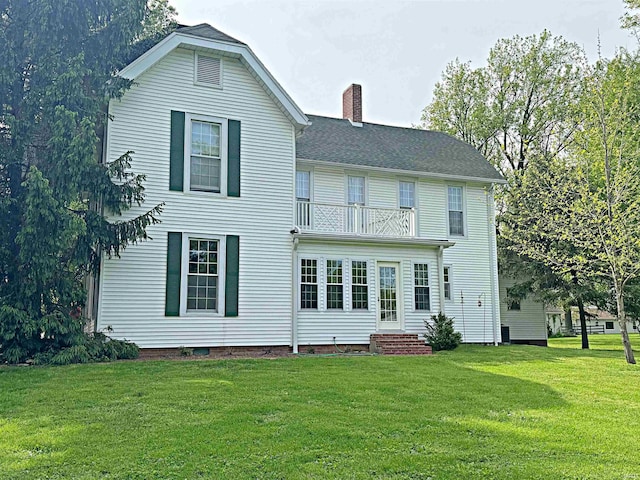 rear view of house featuring a yard and a balcony