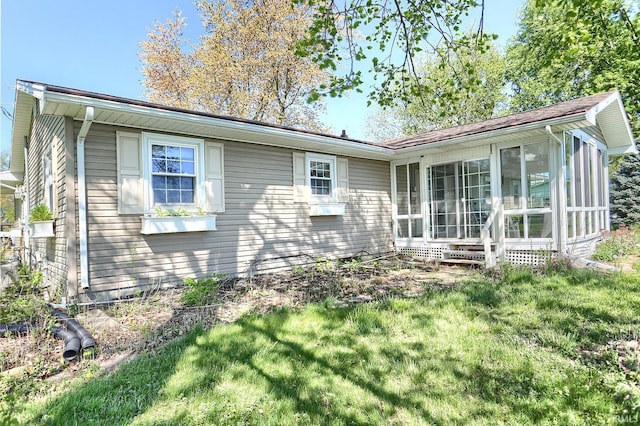 rear view of property featuring a sunroom and a yard