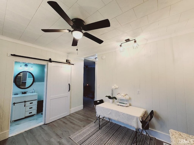 interior space with a barn door, wood-type flooring, and ceiling fan