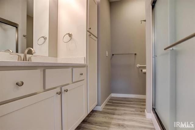 bathroom with vanity, a shower with shower door, and wood-type flooring