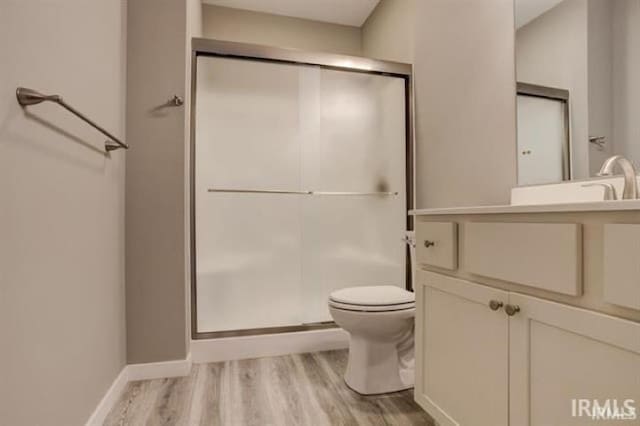 bathroom with walk in shower, vanity, toilet, and hardwood / wood-style floors