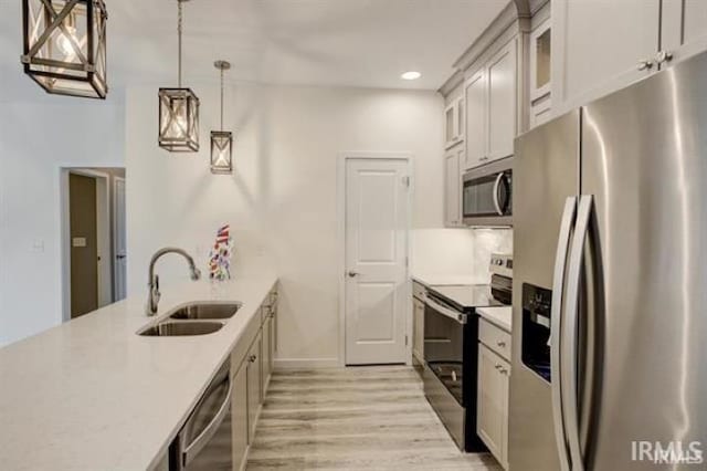 kitchen with hanging light fixtures, light wood-type flooring, sink, and appliances with stainless steel finishes