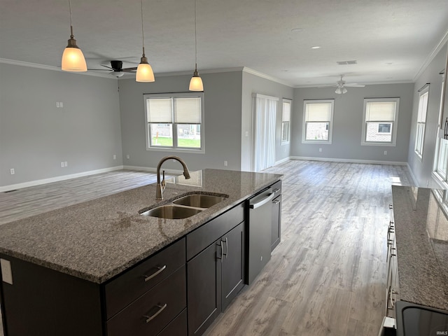 kitchen with dark stone counters, ceiling fan, an island with sink, light wood-type flooring, and sink