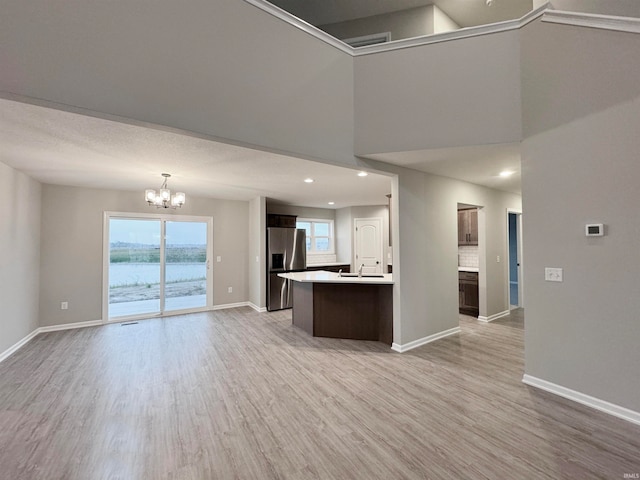 kitchen with plenty of natural light, an inviting chandelier, light wood-type flooring, and stainless steel fridge with ice dispenser