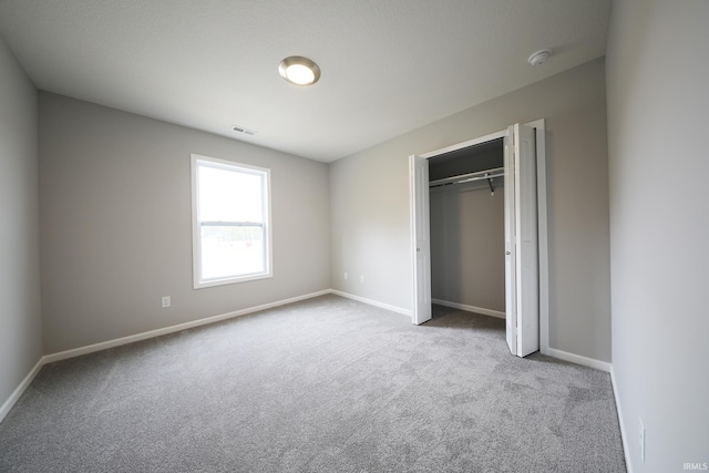 unfurnished bedroom featuring light colored carpet and a closet