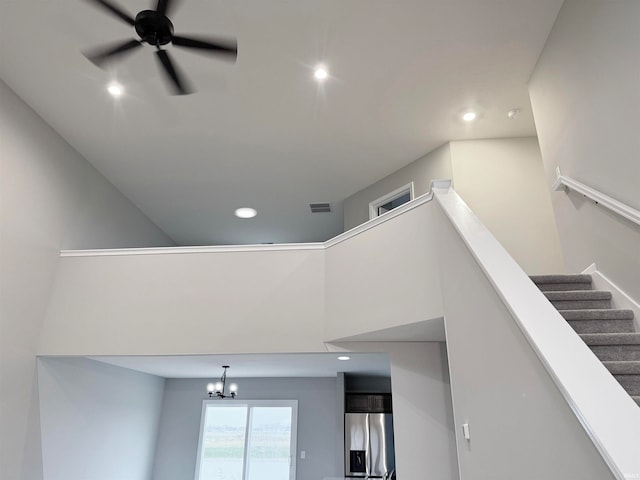 stairway featuring a towering ceiling and ceiling fan with notable chandelier